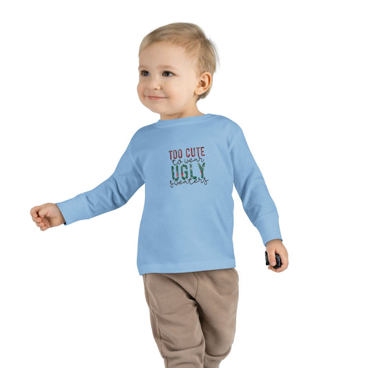Toddler wearing a light blue “Too Cute to Wear Ugly Sweaters” holiday long-sleeve tee from DJ’s Giggle Wear.